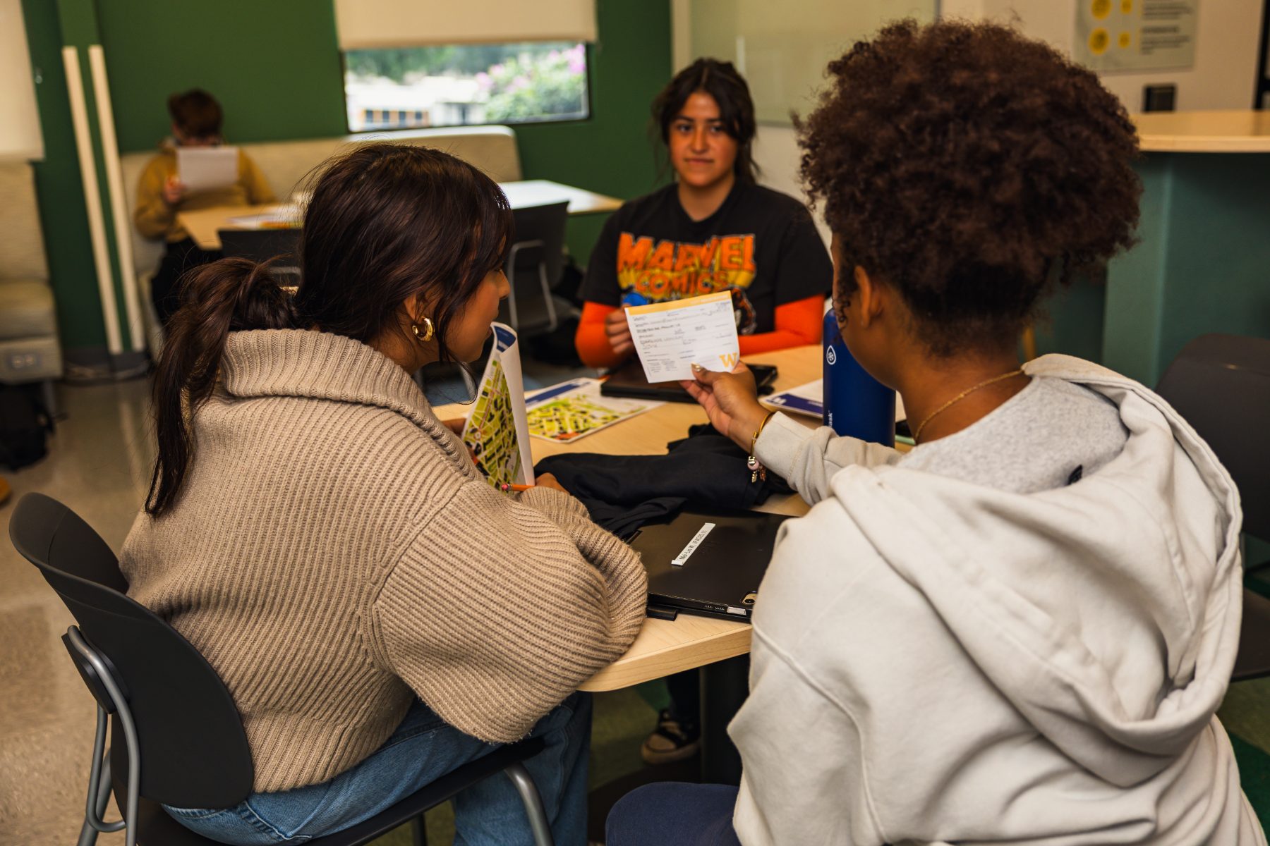 Students comparing paperwork around an advisory table