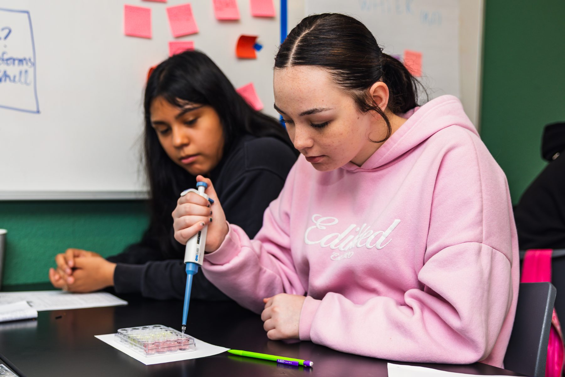 A student using a pipette while a classmate observes